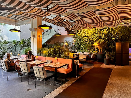 The covered terrace at Slim’s Bal Harbour, with striped canopy and lush greenery